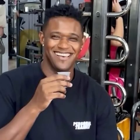 Felipe Mota sorrindo, sentado na academia, de camiseta preta Personal Trainer